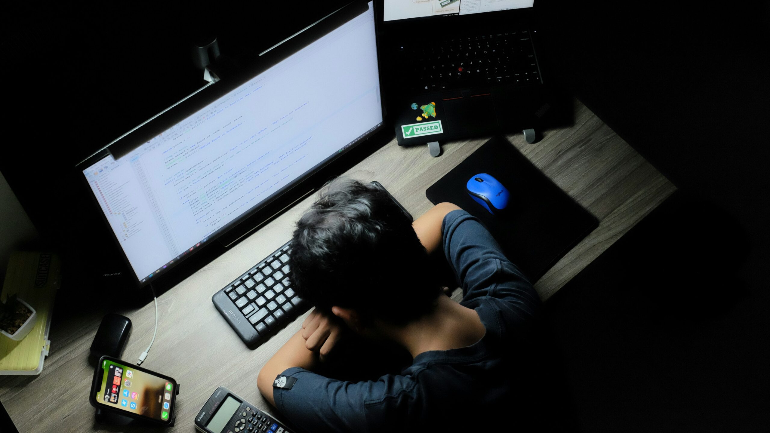 A man with his head on a desk in front of a computer