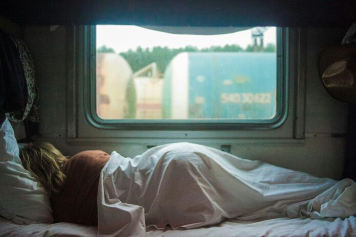 A woman lying down in bed in front of a window